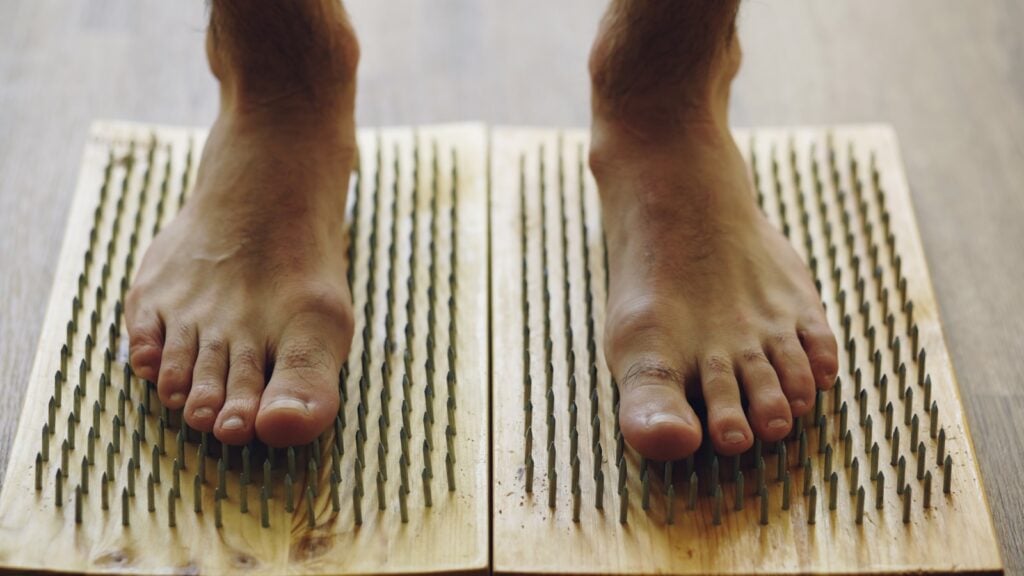 Feet standing on wooden boards with nails. Foot Reflexology Chart and Pressure Points
