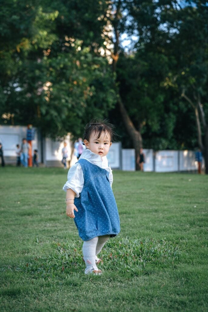 A young child in a blue dress on grass