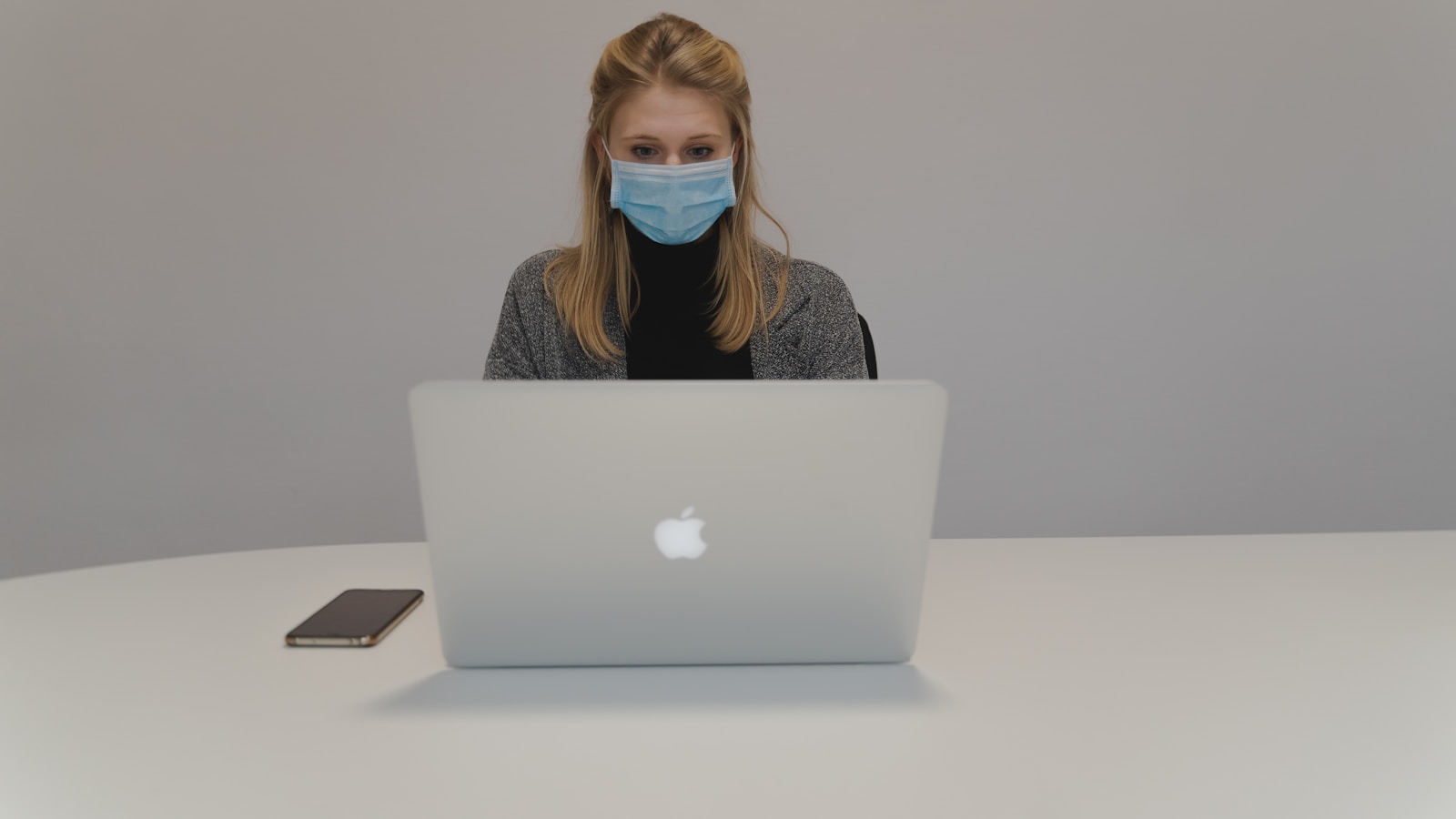 woman in gray sweater using silver macbook