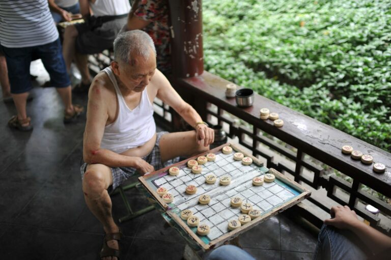 Elderly man playing chinese chess outdoors