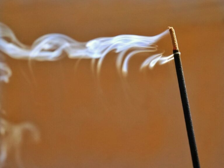 A close up of a incense stick with smoke coming out of it