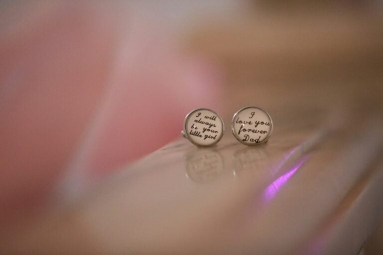 Two round earrings with handwritten text.