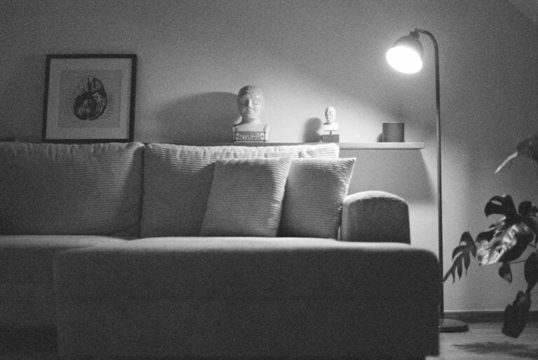 A dimly lit living room with a sofa and lamp.