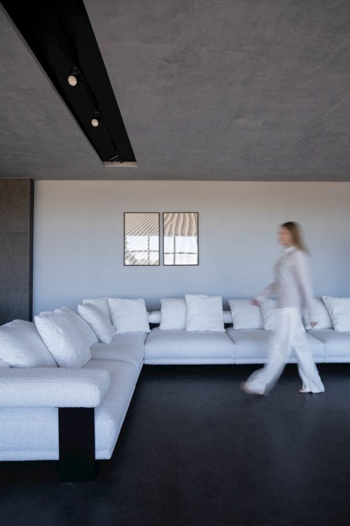 Woman walking past a large white sectional sofa.