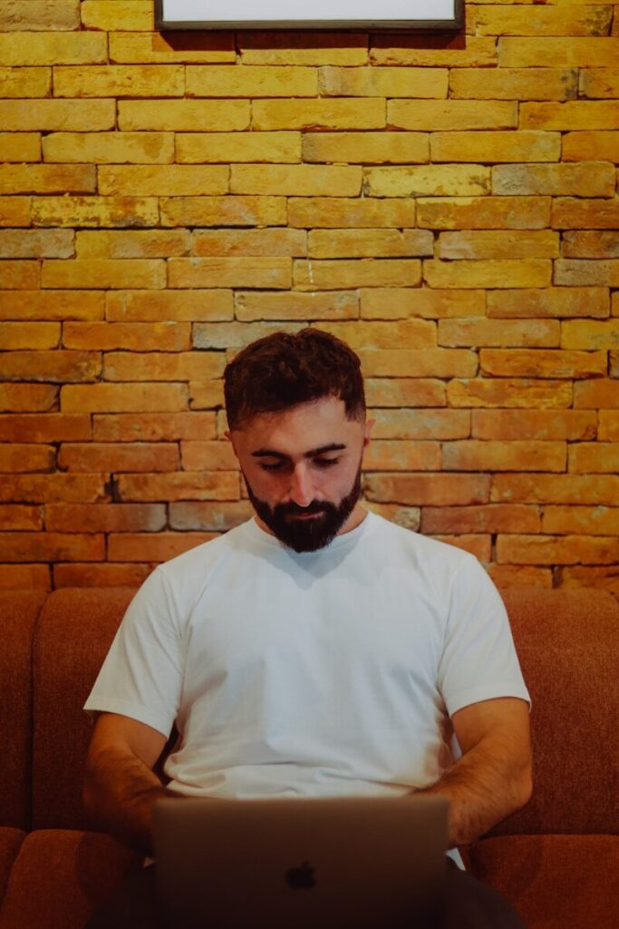 Man in white shirt working on laptop on couch