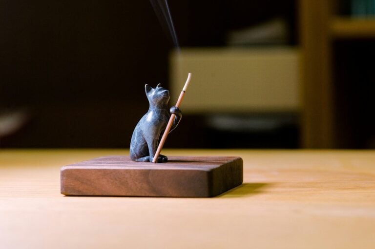 a small statue of a cat holding a stick