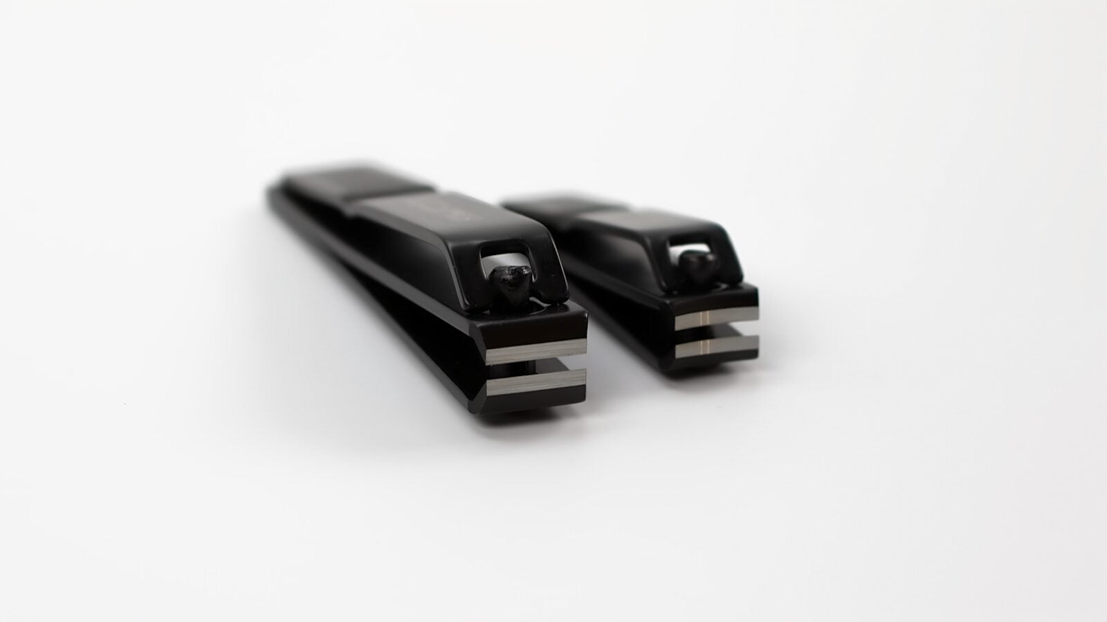 Two black nail clippers on a white background