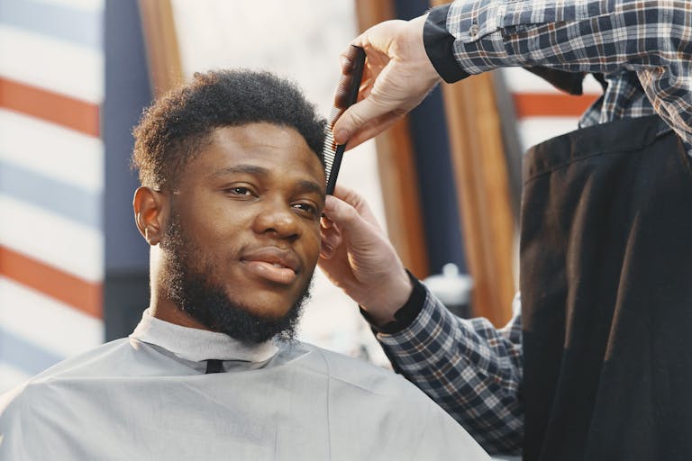 Close-up of a barber styling a bearded man's hair in a modern salon setting.